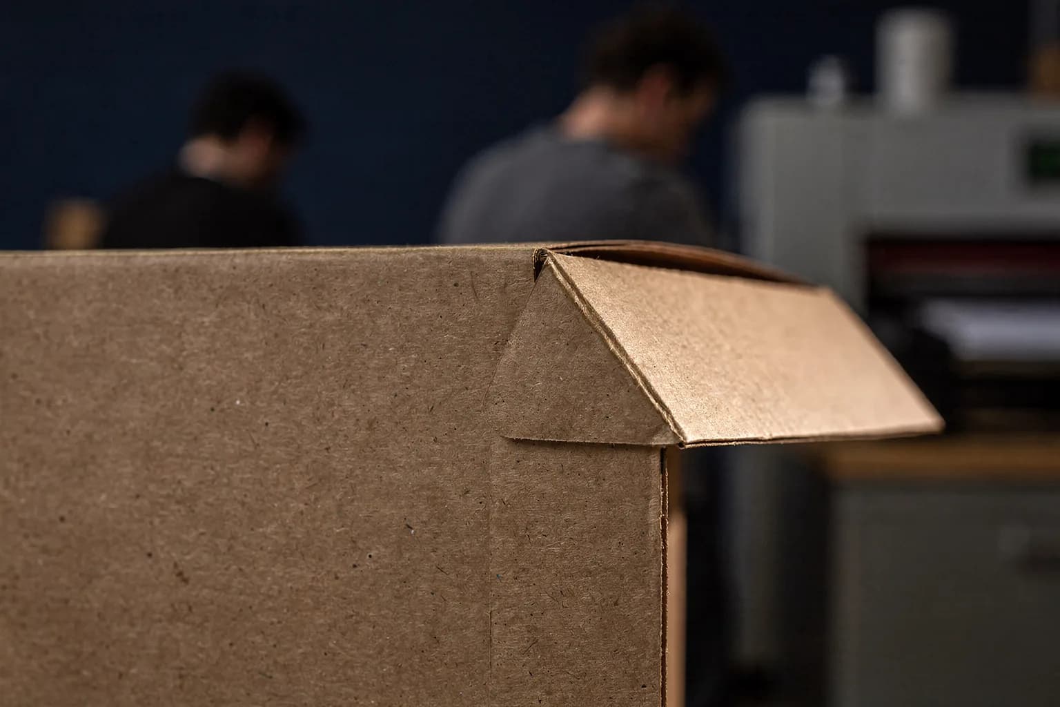 Hände beim Bestücken eines Aktionsdisplays mit Produkten, Nahaufnahme über dem Arbeitstisch, Kartonstruktur sichtbar