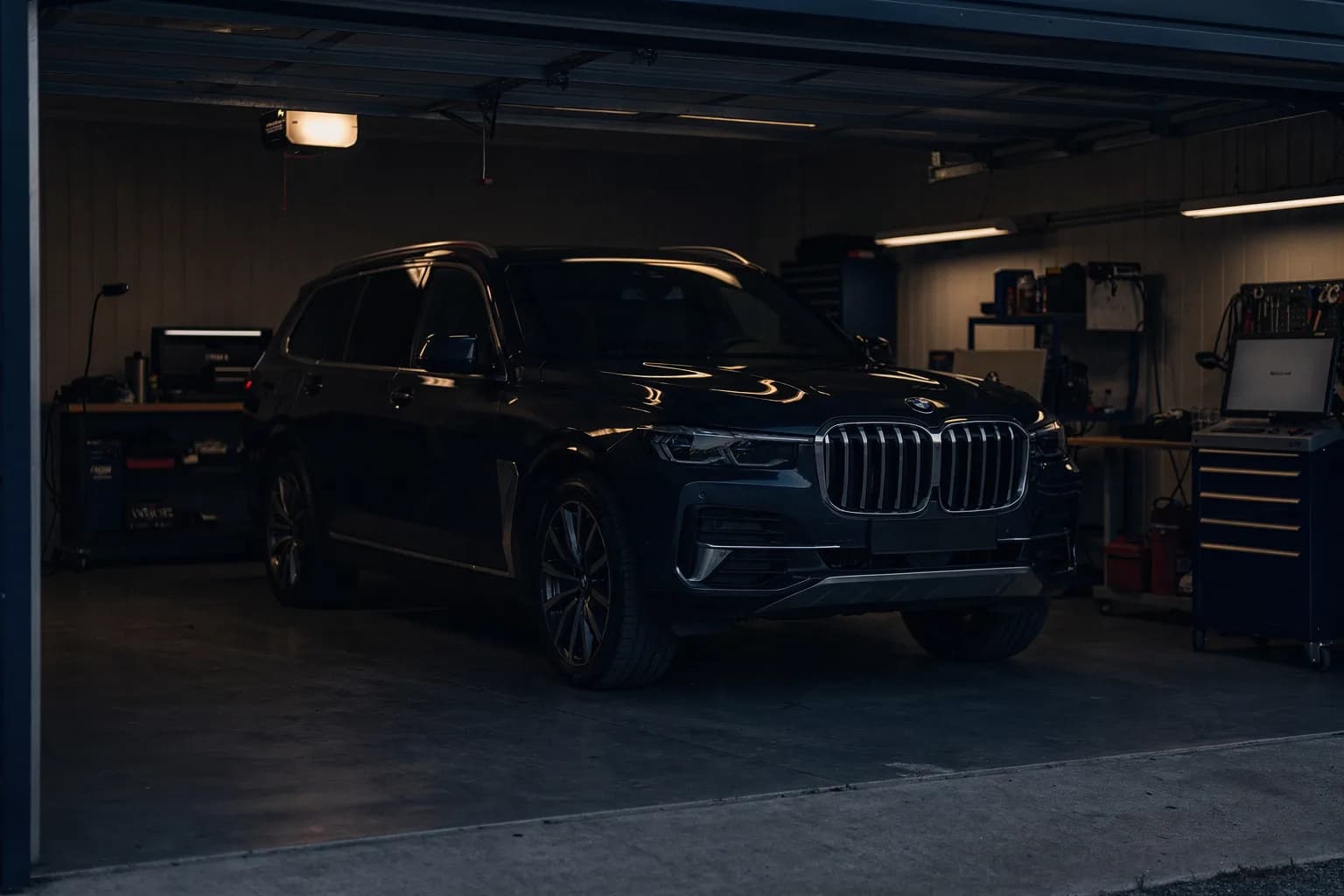 Ruhige Garage im Morgenlicht mit einem dunklen Kombifahrzeug, Türen geschlossen, gekehrter Boden, niemand anwesend, zurückhaltendes Licht