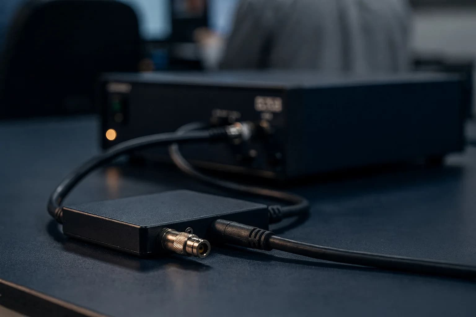 Kalibrieraufbau auf einer Werkbank, ein Kabel führt zu einem Messgerät, kühles Licht mit einer warmen Spiegelung
